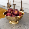 Sir Madam Brass colander with peace sign pattern perforations  with apples inside on a kitchen counter 