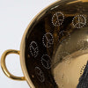 Close up of brass colander with peace sign pattern