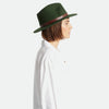 Side view of Brixton brand Messer fedora hat in moss green on model with white shirt and jeans a white background