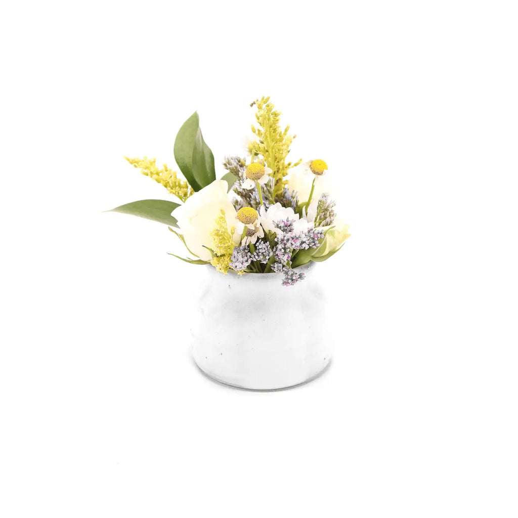 Small white pottery bud vase with flowers on a white background