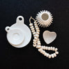 Collection of decorative house accessories including white stoneware heart dish on a black surface