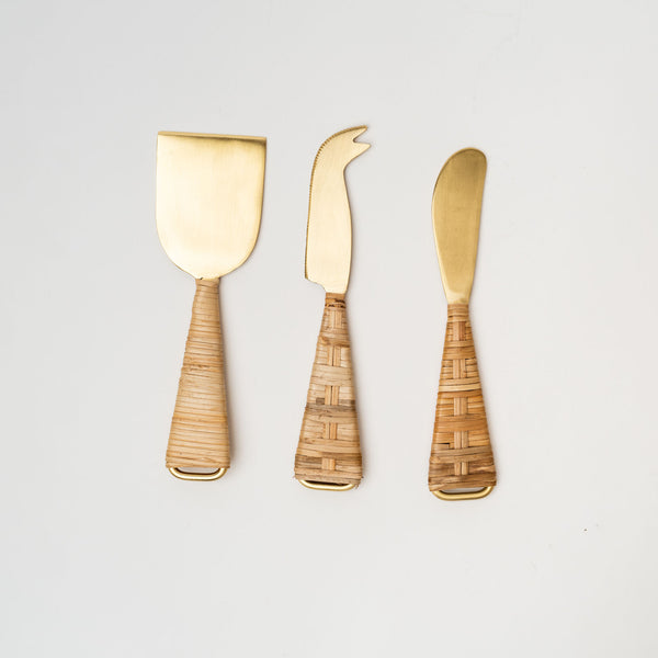 Brass cheese knives with rattan wrapped handles on a white background