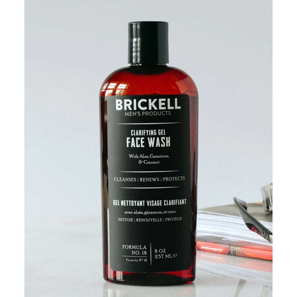 Brown Bottle of Brickell Clarifying Face Wash for Men with black label on a table top with books