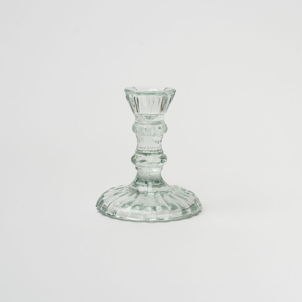 Clear pressed glass candlestick on a white background