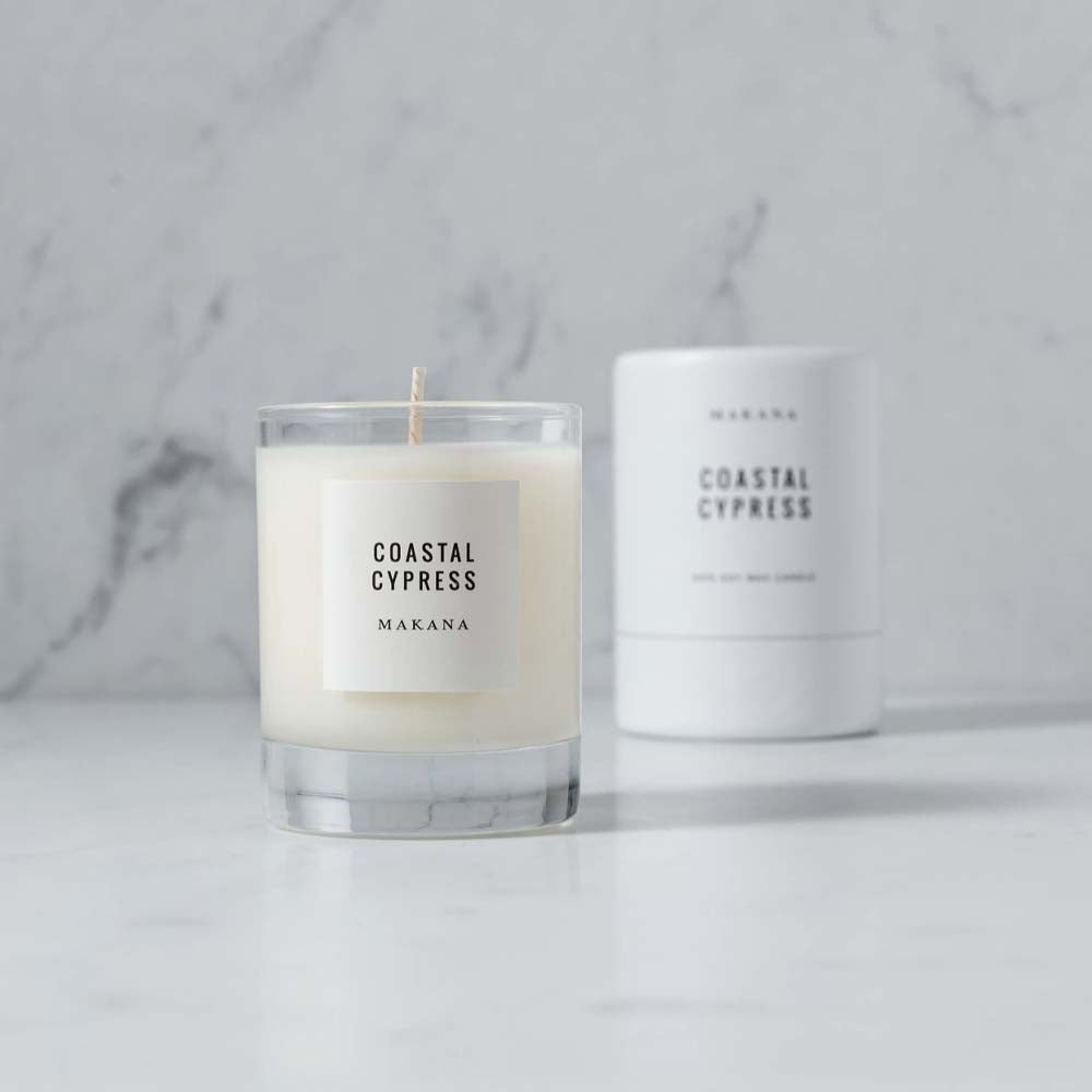 Makana brand coastal cypress glass candle and white candle box on a marble counter