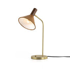 Four hands brand Cullen task lamp in brass with leather shade and walnut accents with bulb lit on a white background