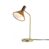 Four hands brand Cullen task lamp in brass with leather shade and walnut accents with bulb lit on a white background