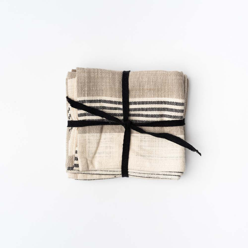 Set of three natural and black stripe tea towels tied with black ribbon on white background