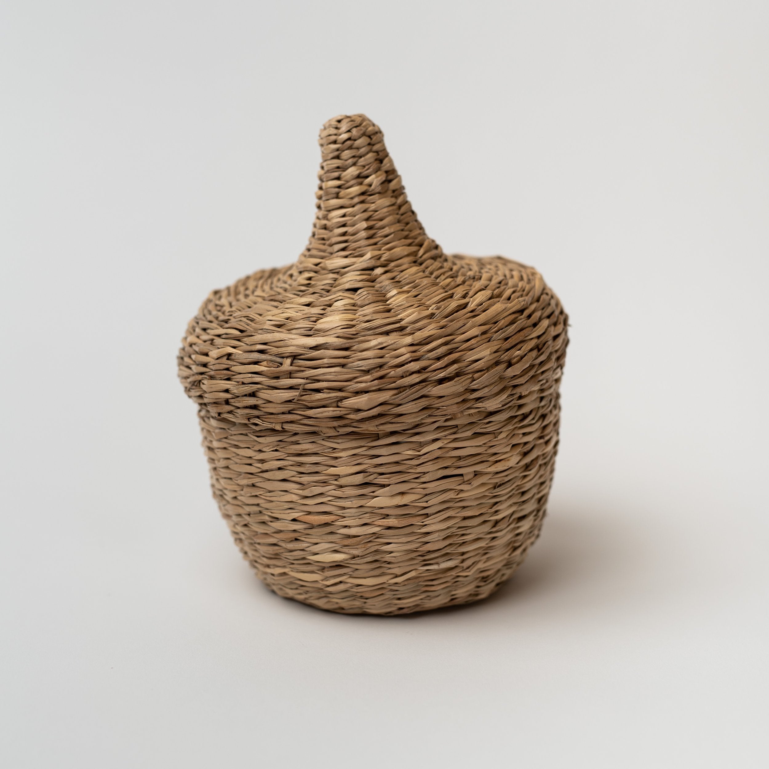 Small seagrass baskets with lid that look like an acorn on a white background