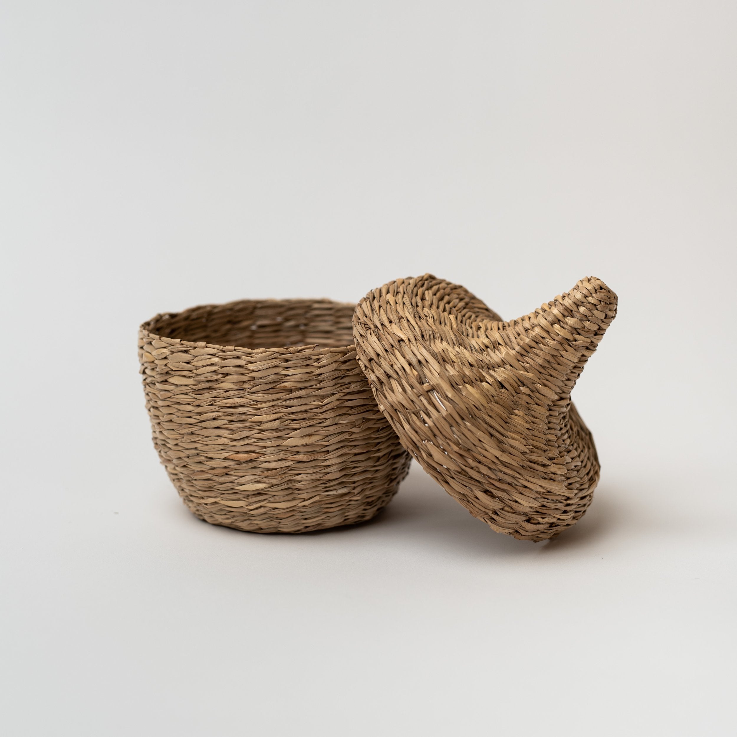 Small seagrass baskets with lid taken off on a white background