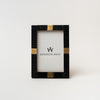 Black bone picture frame with square brass accents on a white background