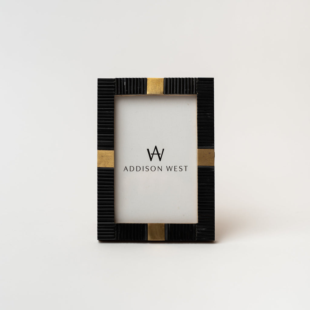 Black bone picture frame with square brass accents on a white background