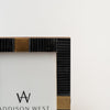 Close up black bone picture frame with square brass accents on a white background