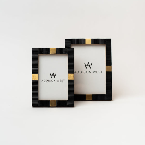 Two black and brass picture frames on a white background