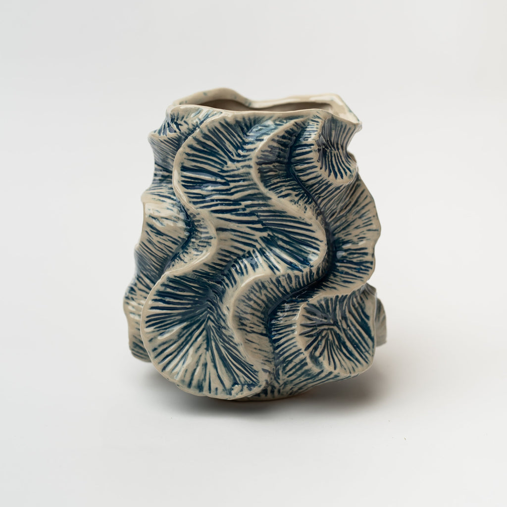 Cream vase with blue flutter pattern on a white background
