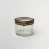 Round beveled glass box with brass snap lid on a white background