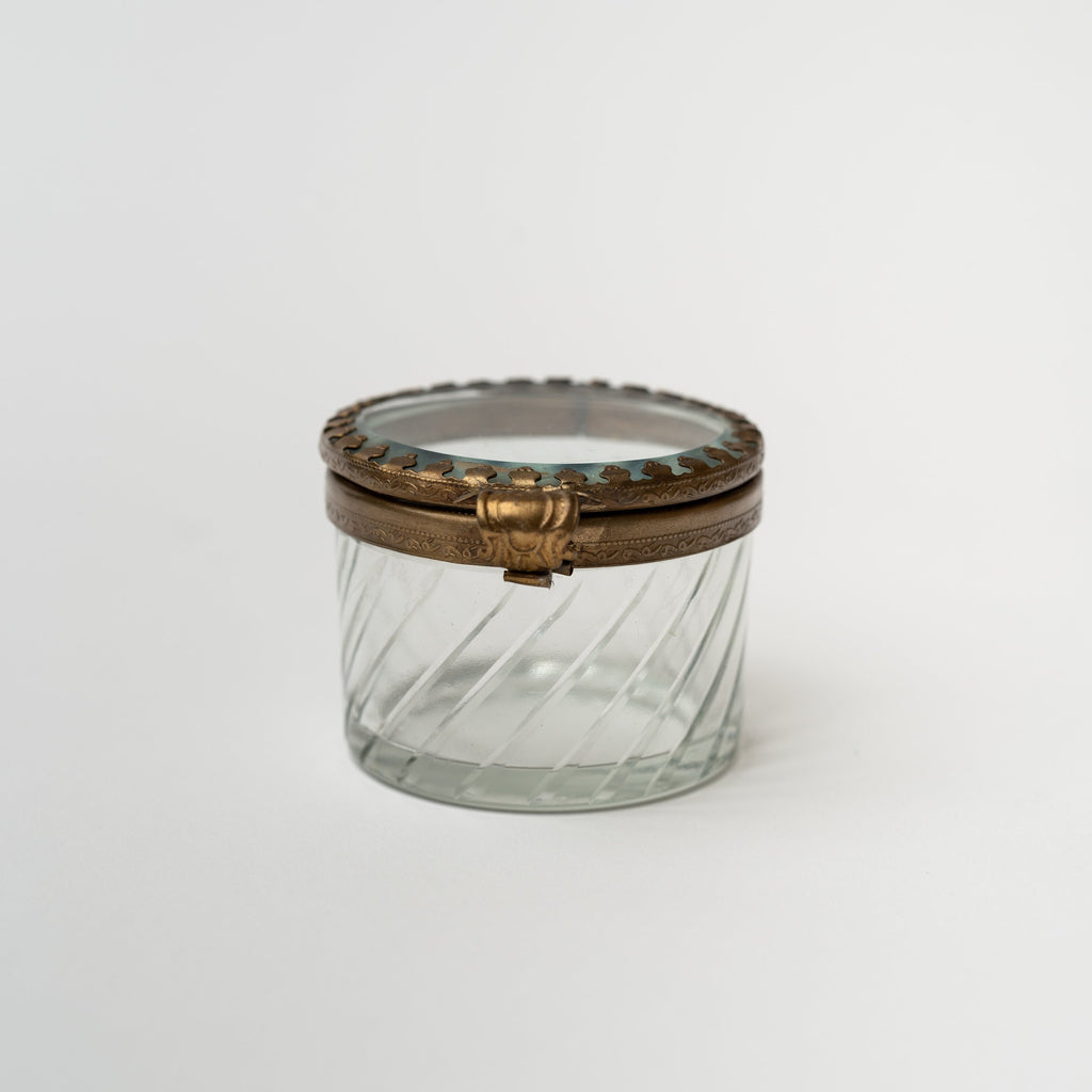 Round beveled glass box with brass snap lid on a white background