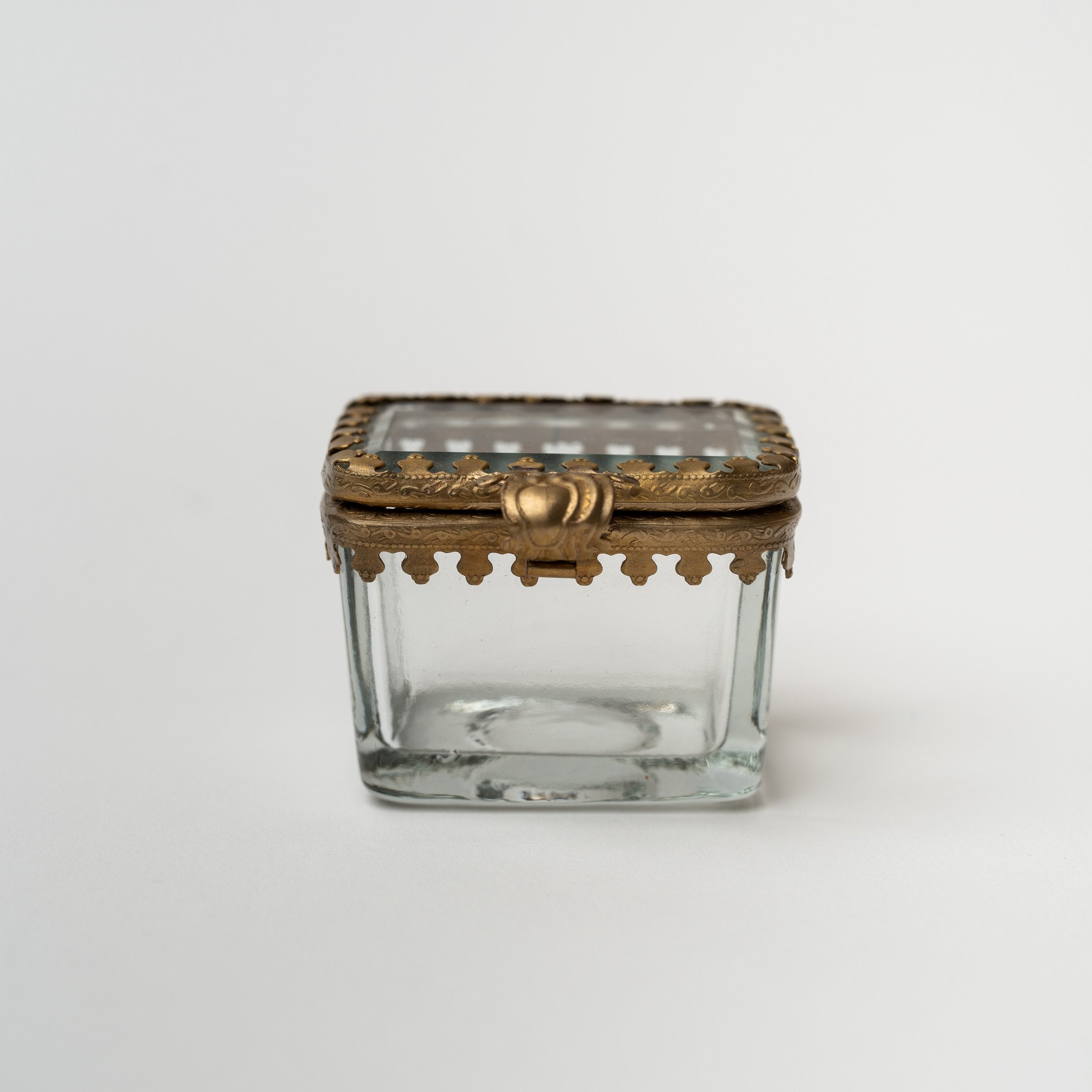 Rectangular beveled glass box with brass snap lid on a white background