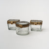 Three beveled glass boxes with brass snap lids on a white background