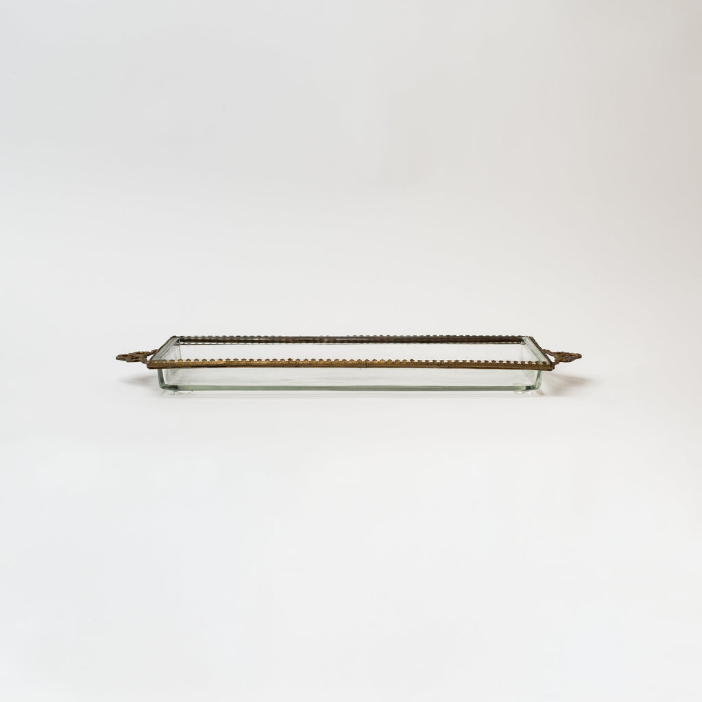Glass tray with metal brass scallop edging and decorative metal bows on ends on a white background