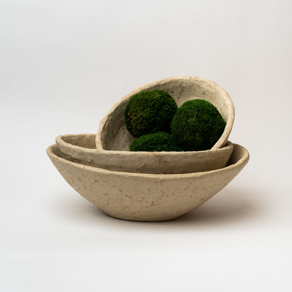 Three paper mache bowls nested with moss balls on a white background