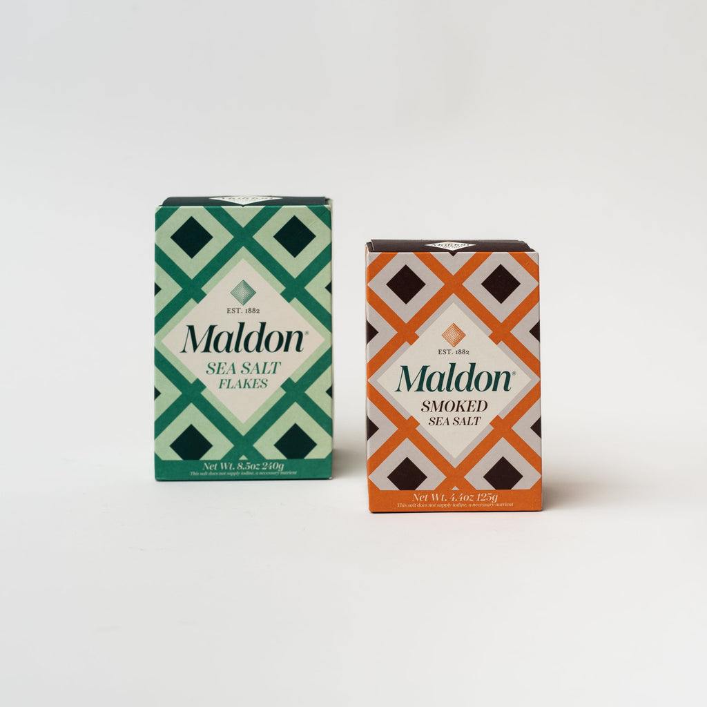 Two boxes of plain and smoked Malden salt on a white background
