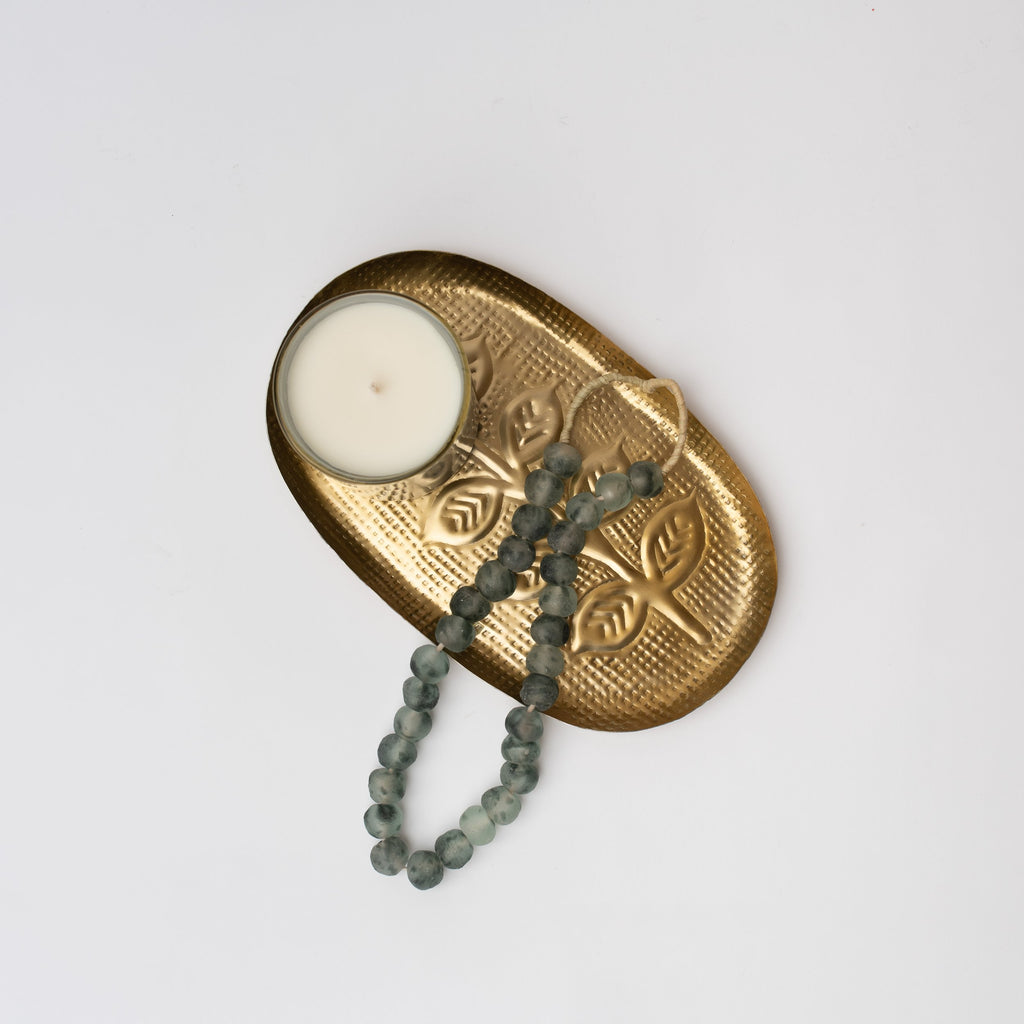 Blue grey colored decorative glass beads on a brass tray with candle 