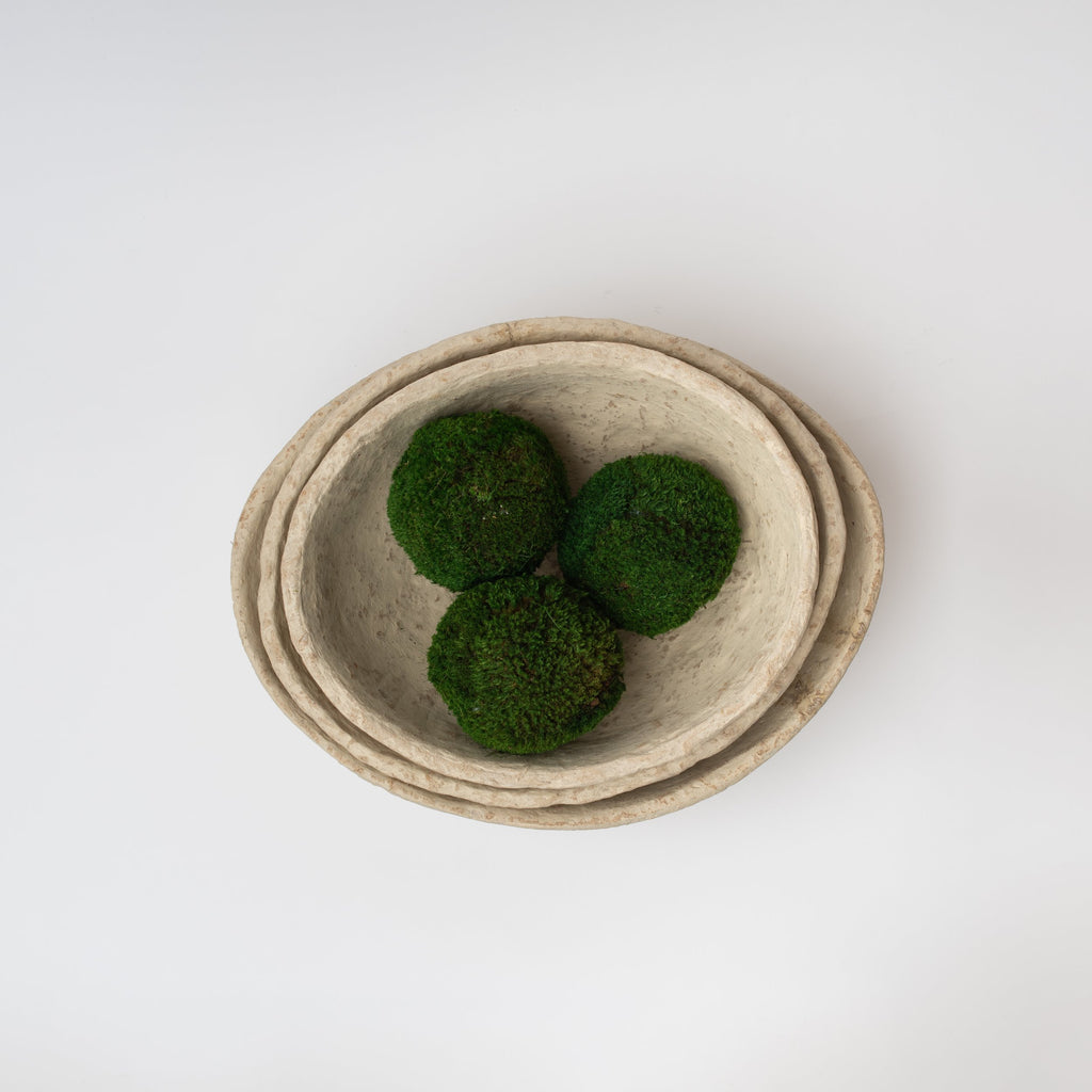 Three paper mache bowls nested with moss balls on a white background viewed from above