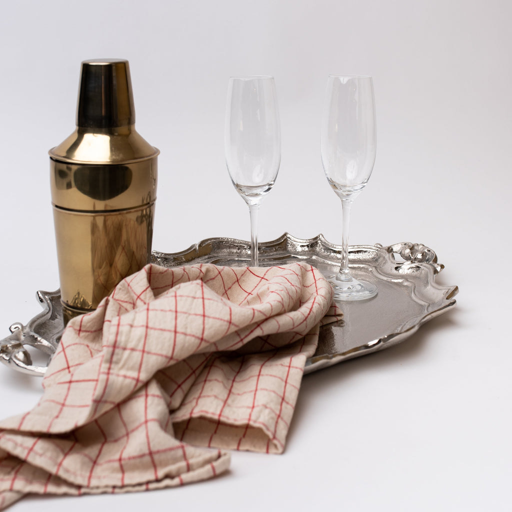 Silver tray with champagne glasses and shaker and bar towel on a white background