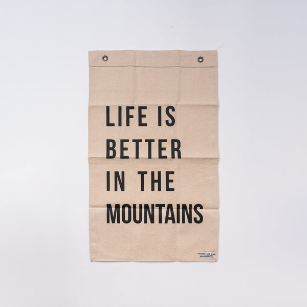Pointer and Pine brand natural flag with black letters that says Life is Better in the Mountains