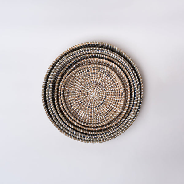 Nested round sea grass trays on a white background
