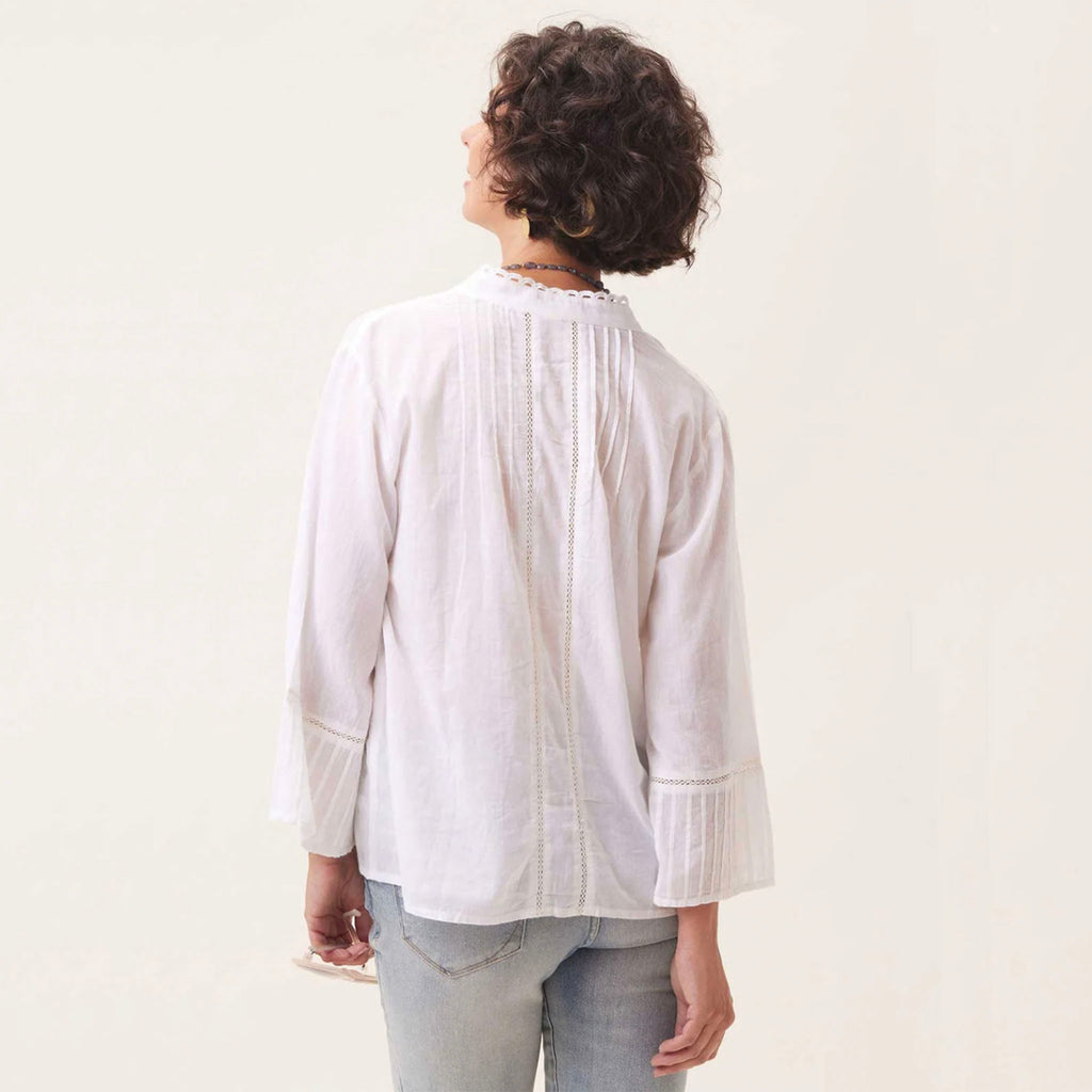 Model wearing white lightweight cotton top with pleat sleeve and a jeans in front of a white backdrop