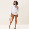 Model wearing white lightweight cotton top with pleat sleeve and shorts in front of a white backdrop 