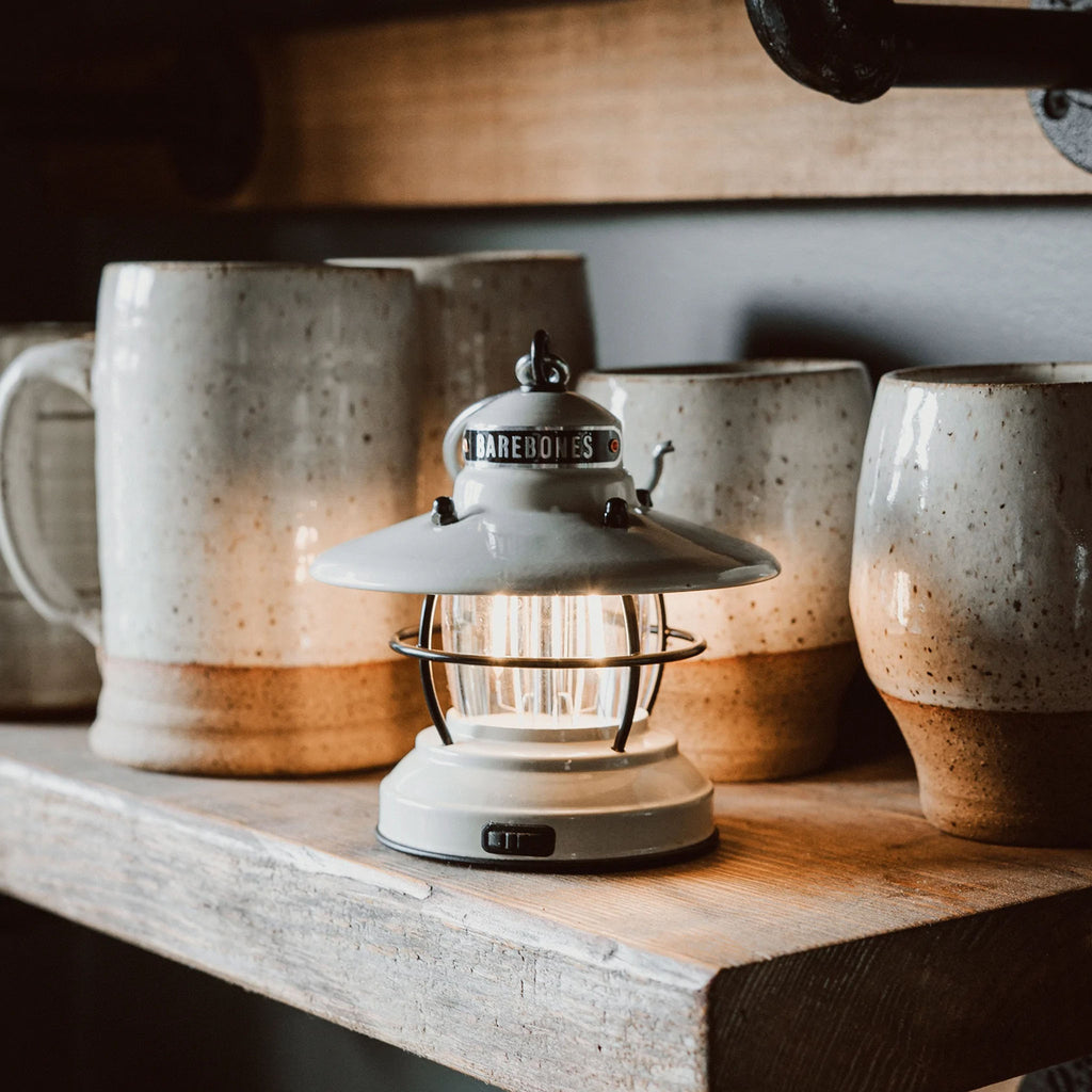 White mini Edison lantern by Barebones brand with vintage style and caged bulb on a shelf with mugs