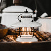 White mini Edison lantern by Barebones brand with vintage style and caged bulb on a plaid napkin
