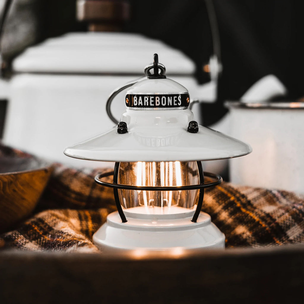 White mini Edison lantern by Barebones brand with vintage style and caged bulb on a plaid napkin