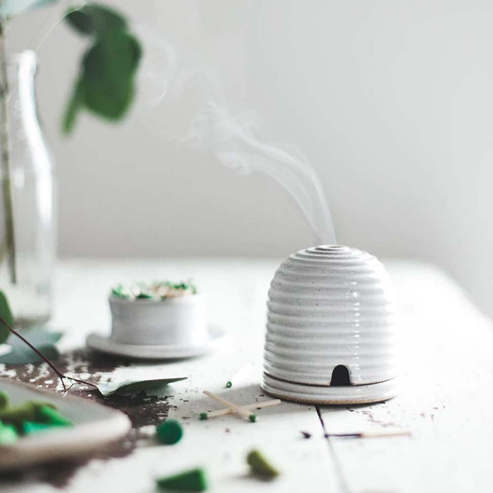 Farmhouse Pottery Beehive Burner lit on a table with matches nearby