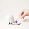 Farmhouse Pottery Beehive Burner being lit with a hand and match on a white background
