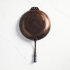 Underside of Smithey farmhouse carbon steep skillet on a white background