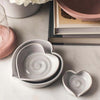 Farmhouse pottery brand heart dish set on a counter with books
