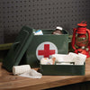 Green metal first aid box with white circle and Red Cross on on a shelf with old lantern