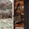 Bare bones brand foraging back in dark khaki on a hook on log cabin wall