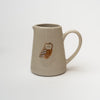 Small pitcher with owl painted on front on a white background