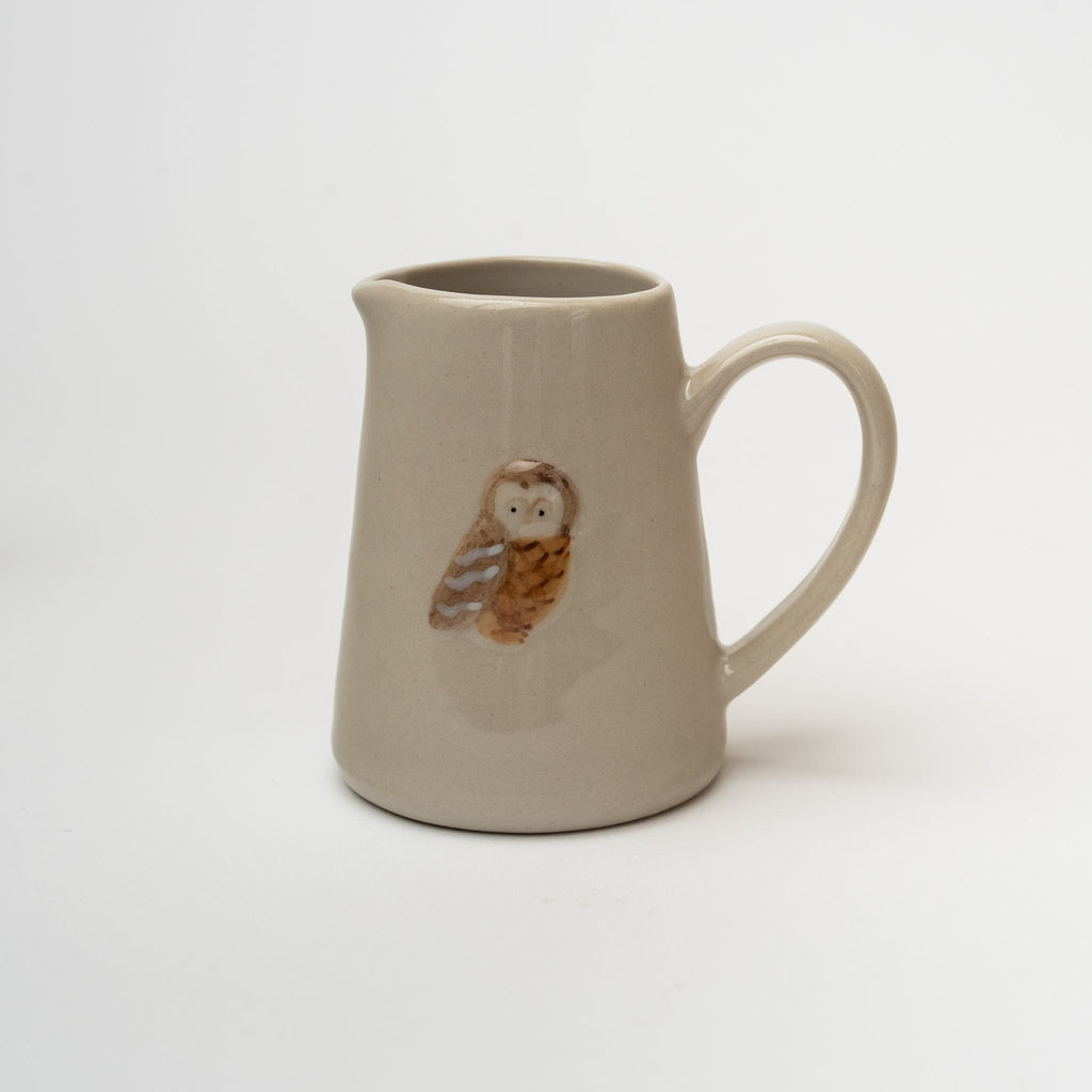 Small pitcher with owl painted on front on a white background