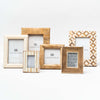 Collection of white, rattan and wood toned picture frames on white background