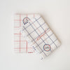 Set of two red and blue plaid Tissage de L’Ouest tea towels with made in france sticker on a white background