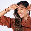 Model wearing ink and alloy brand colorful stretch bracelets with a rust colored sweater on a white background