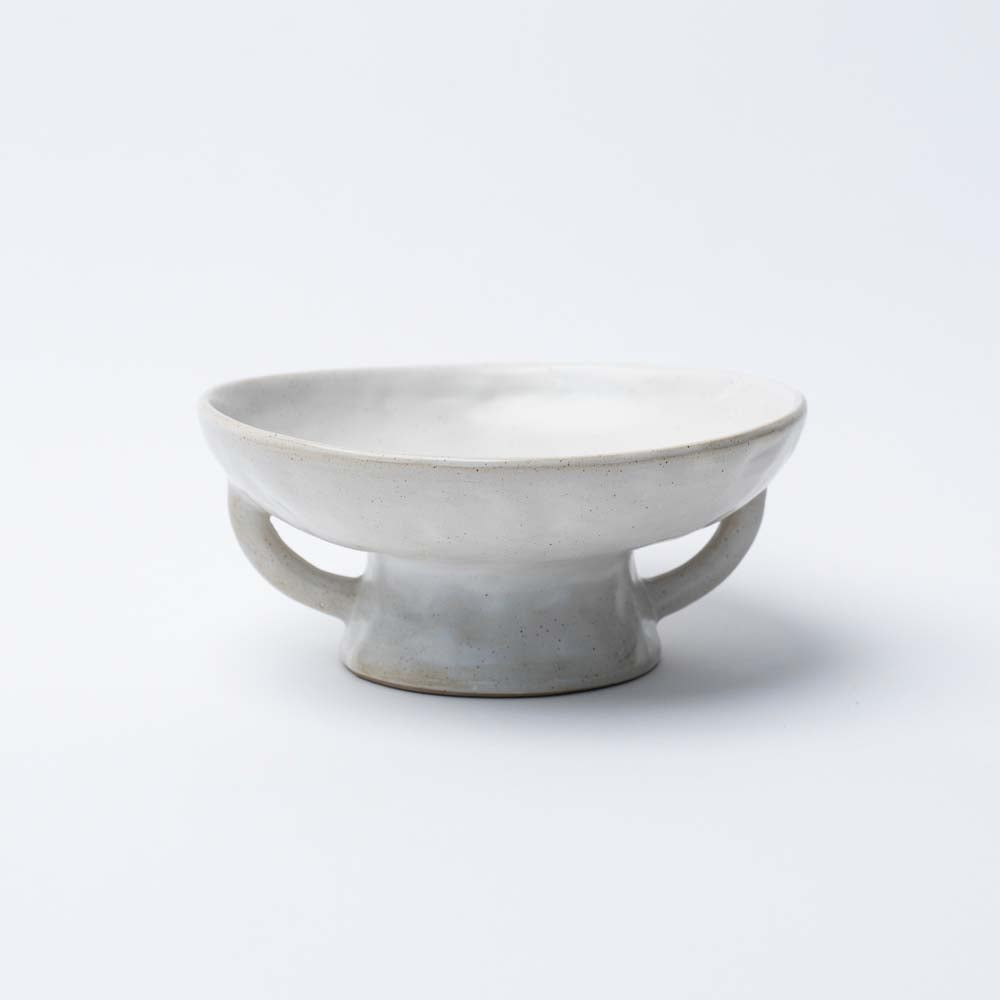 White stoneware pedestal bowl with two handles on a white background