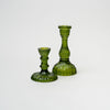 Set of green cut glass candle sticks on a white background
