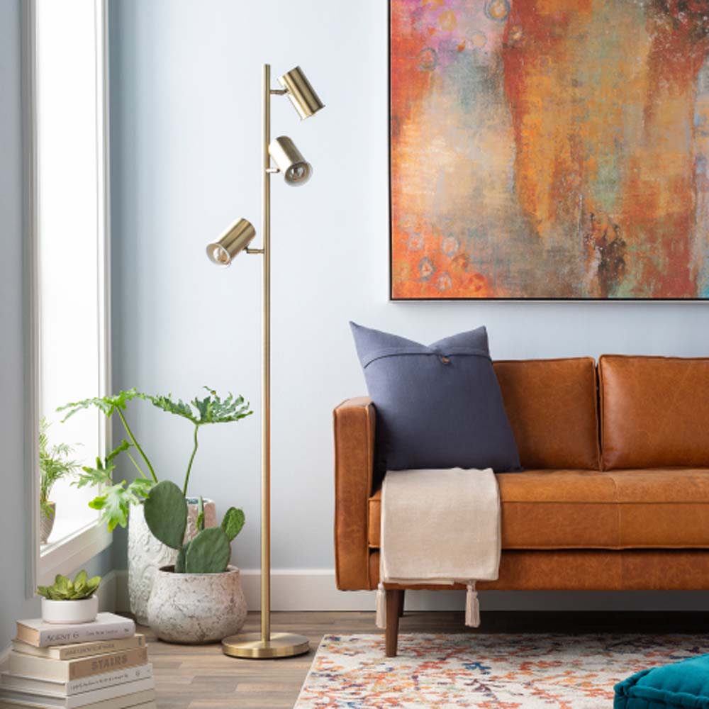 Brass Surya Hammond floor lamp with three shades in a living space with an organge couch